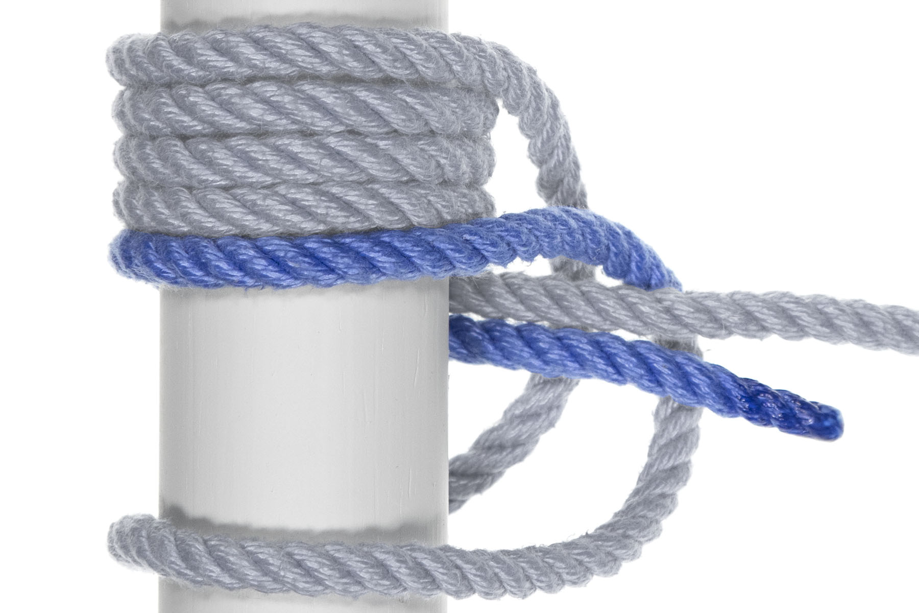 This part is tricky.The working end goes over the pole, stacked directly beneath the three original wraps around the pole. It makes a 180 degree turn around the pole, directly next to the lowest wrap, and exits to the right, snug against the standing part. Following the standing part, it crosses over the two parts of the rope that originally crossed under the standing part.